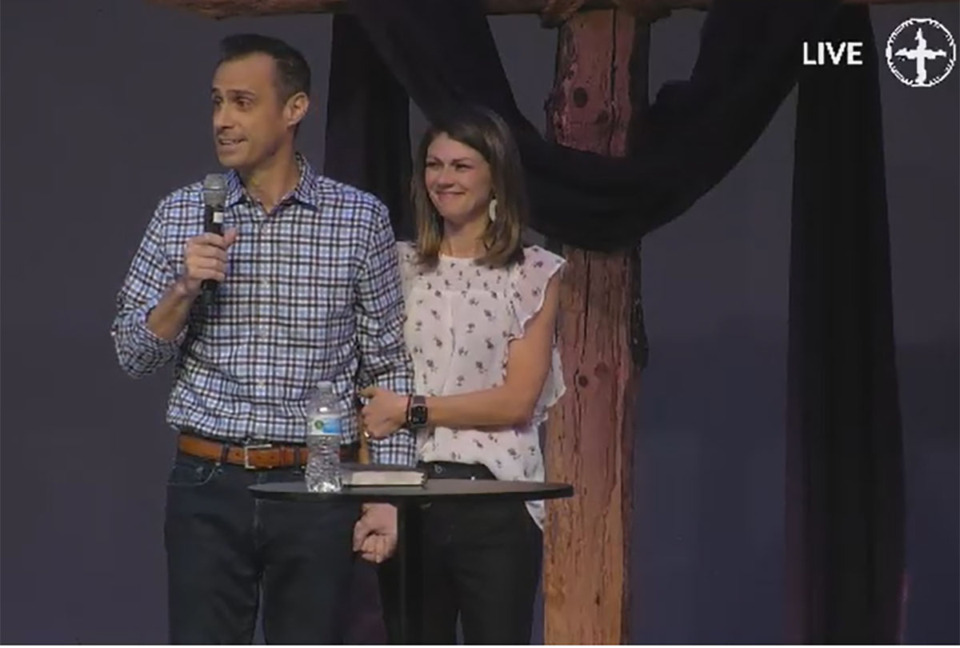 <strong>Kennon Vaughan, accompanied by his wife Kathryn, (right) speaks to the congregation of Harvest Church nine weeks after surviving a plane crash that left four members of the church dead. Vaughan was the sole survivor of the crash.</strong> (Screenshot courtesy Harvest Church)