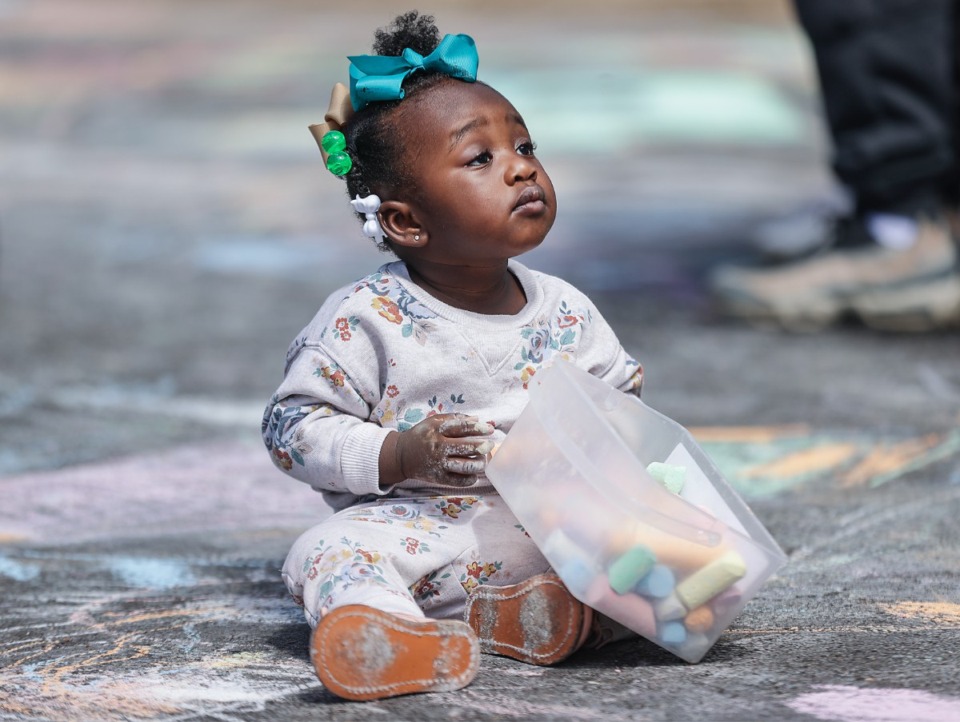 <strong>Na'Siya Jordon, 1, plays with a box of chalk at the Brooks Museum's Chalkfest March 25, 2023.</strong> (Patrick Lantrip/The Daily Memphian)