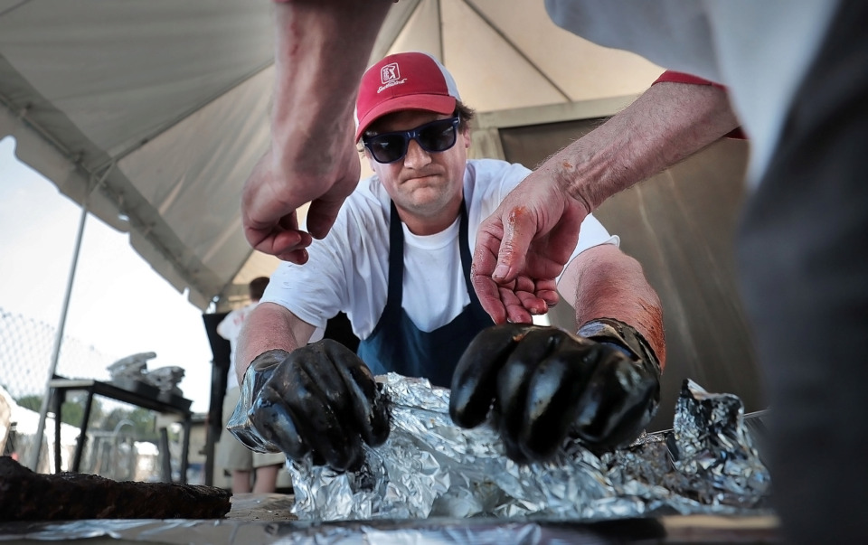 <strong>Schaefer Rowe with Redneck Bar-B-Que Express, one of the oldest teams still competing, unwraps ribs fresh from the smoker during the first day of the 2019 Memphis in May World Championship Barbecue Cooking Contest at Tom Lee Park on May 15, 2019.</strong> (Jim Weber/Daily Memphian)
