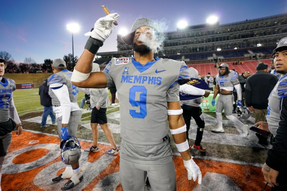 <strong>Memphis linebacker Geoffrey Cantin-Arku (9) smokes a cigar on the field following the First Responder Bowl NCAA college football game against Utah State, Tuesday, Dec. 27, 2022, in Dallas. Memphis won 38-10.</strong> (AP Photo/Sam Hodde)