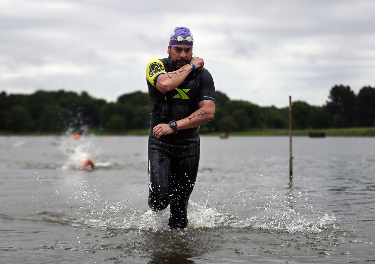 <strong>Francisco Alatorre works to quickly remove his wetsuit as he emerges from the water en route to the bicycle portion of the Memphis in May Olympic Triathlon on Sunday, May 19.</strong> (Patrick Lantrip/Daily Memphian)
