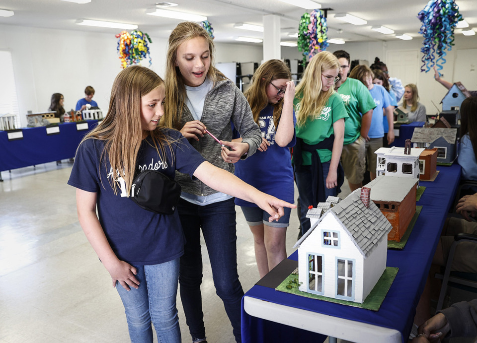 <strong>DeSoto Christian Academy fifth graders Khloe Courtney (left) and Charliee Rutherford (right) look over the freshman classes table top model houses made by using recycled materials May 3.</strong> (Mark Weber/The Daily Memphian)