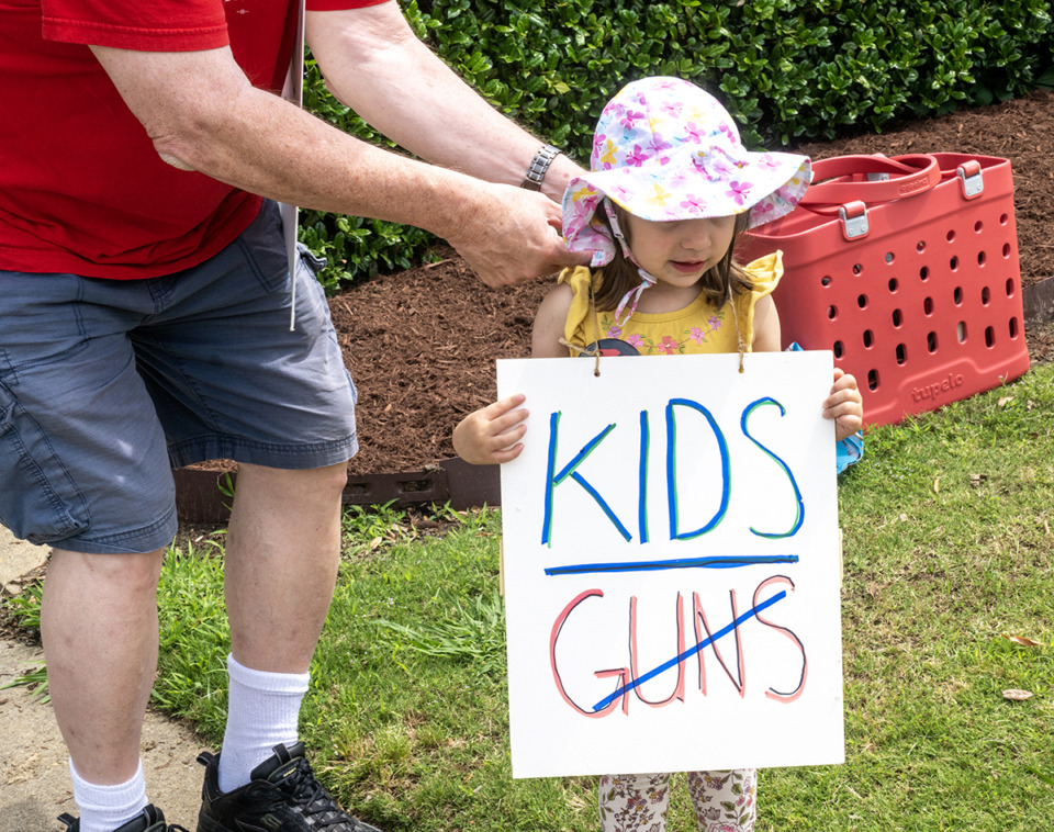 <strong>Lena Cambron, 3, gets her sun protection on from her grandfather, Dave Cambron at the start of the gun control rally. The group protested in Collierville at the corner of Poplar Avenue and Byhalia Road, Saturday, May 13.</strong> (Greg Campbell/Special for The Daily Memphian)