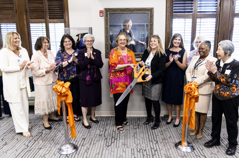 <strong>Dr. Wendy Likes, dean of UTHSC College of Nursing (fifth from right in black jacket) and colleagues cut the ribbon on the Dr. Margaret A. Newman Center for Nursing Theory in front of a newly unveiled portrait of Dr. Newman.</strong> (Courtesy UTHSC)