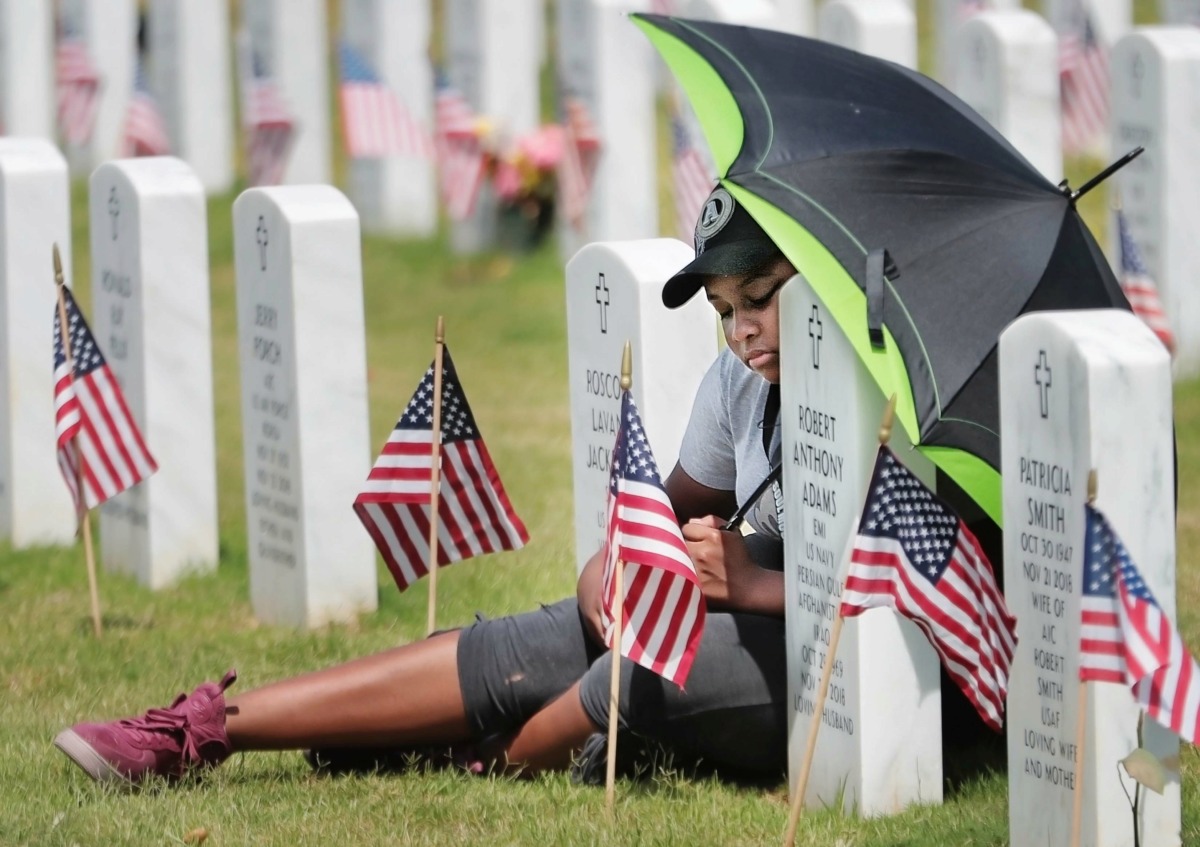 <strong>Camaya Clark visits her uncle's grave marker before the start of the annual Memorial Day ceremony at the West Tennessee State Veterans Cemetery on Monday, May 27. Robert Adams was a Navy petty officer who served in three separate conflicts.</strong> (Jim Weber/Daily Memphian)