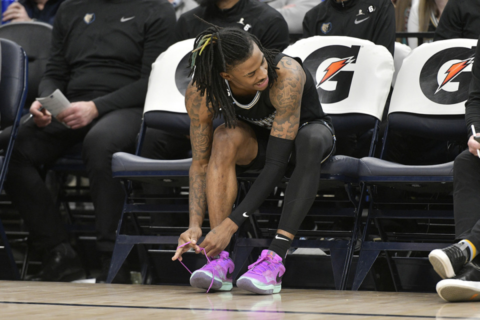 <strong>Memphis Grizzlies guard Ja Morant ties his signature Nike shoe, the Ja 1s, on the bench in the game against the Phoenix Suns Tuesday, Dec. 27, 2022 at FedExForum. Nike has voiced its support for Morant during his suspension.</strong> (Brandon Dill/AP Photo file)
