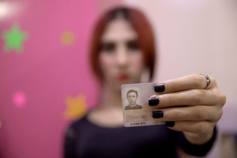 <strong>A transgender woman holds an identification card that has not been changed after her transition.</strong> (Nariman El-Mofty/AP file)