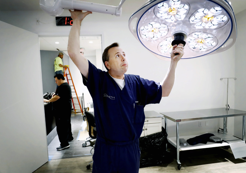 <strong>Dr. Phillip Zeni Jr. moves a lamp as he sets up a procedure room at his new spa-like aesthetics clinic inside the old Lulumelon location in Regalia Shopping center Tuesday, June 11, 2019. </strong>(Mark Weber/Daily Memphian)