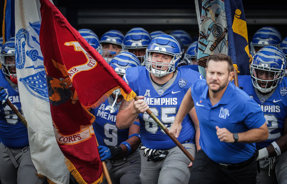 <strong>Offensive lineman Noah Gambill (65) carries a United States Marine Corps flag as coach Ryan Silverfield and the University of Memphis Tigers take the field before a Sept. 15 game against Navy at Simmons Bank Liberty Stadium.</strong> (Patrick Lantrip/The Daily Memphian)