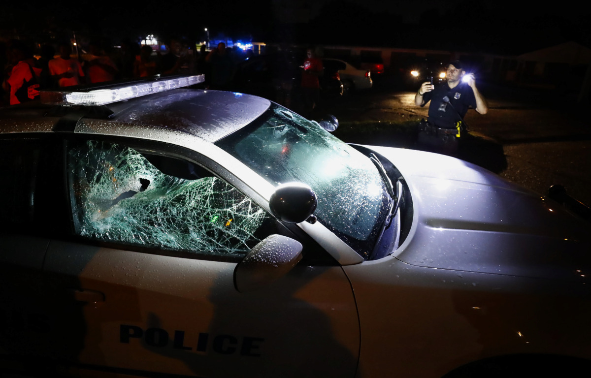 <strong>A Memphis police officer looks over a damaged squad car after protesters took to the streets of Frayser in anger over the shooting of a youth U.S. Marshals earlier Wednesday. Dozens of protesters clashed with police, throwing stones and tree limbs until police forces broke up the angry crowd with tear gas.</strong> (Mark Weber/Daily Memphian)