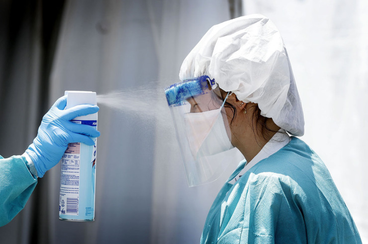 <strong>A Christ Community Health Center medical staff member is sprayed with Lysol while collecting nasal swabs as hundreds of Memphians line up for COVID-19 testing in Hickory Hill on July 14, 2020.</strong> (Mark Weber/The Daily Memphian file)