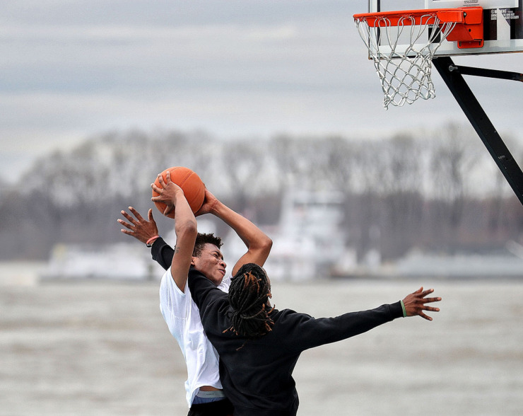 <strong>Cortavius Thompson (left) and Duke Warren play a game of one-on-one at the pop up park in the parking lot of Beale Street Landing as barge traffic passes by on the river. The Mississippi is expected to crest next week at 41 feet, the fourth highest level on record for the Memphis area.</strong> (Jim Weber/The Daily Memphian file)
