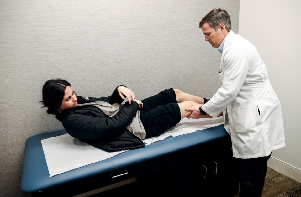 <strong>OrthoSouth orthopedic surgeon Marcus Biggers (right) examines patient Izzy Ellis, 17, (left) on Monday, April 3, 2023, at their newly opened location in Arlington.</strong> <strong>OrthoSouth has signed a 10-year partnership agreement with the Memphis Grizzlies.</strong> (Mark Weber/The Daily Memphian file)&nbsp;