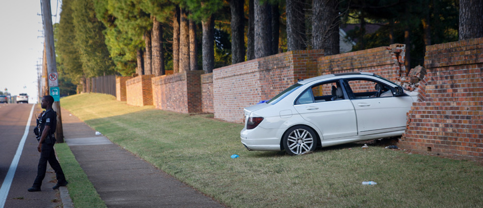 <strong>A Memphis Police Department officer walks on the scene of the accident after a driver crashed into a brick wall in the Lion&rsquo;s Gate neighborhood across from Whitehaven High School after being shot at multiple times on Sept. 27, 2023.</strong> (Aarron Fleming/The Daily Memphian)