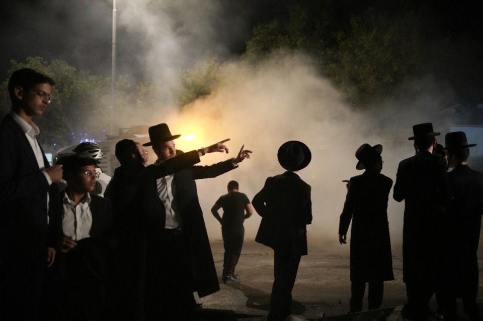 <strong>Ultra-Orthodox Jewish men inspect a damaged road after it was hit by a rocket fired from the Gaza Strip, in the West Bank Jewish settlement of Beitar Illit, Monday, Oct. 9, 2023.</strong> (Maya Alleruzzo/AP)