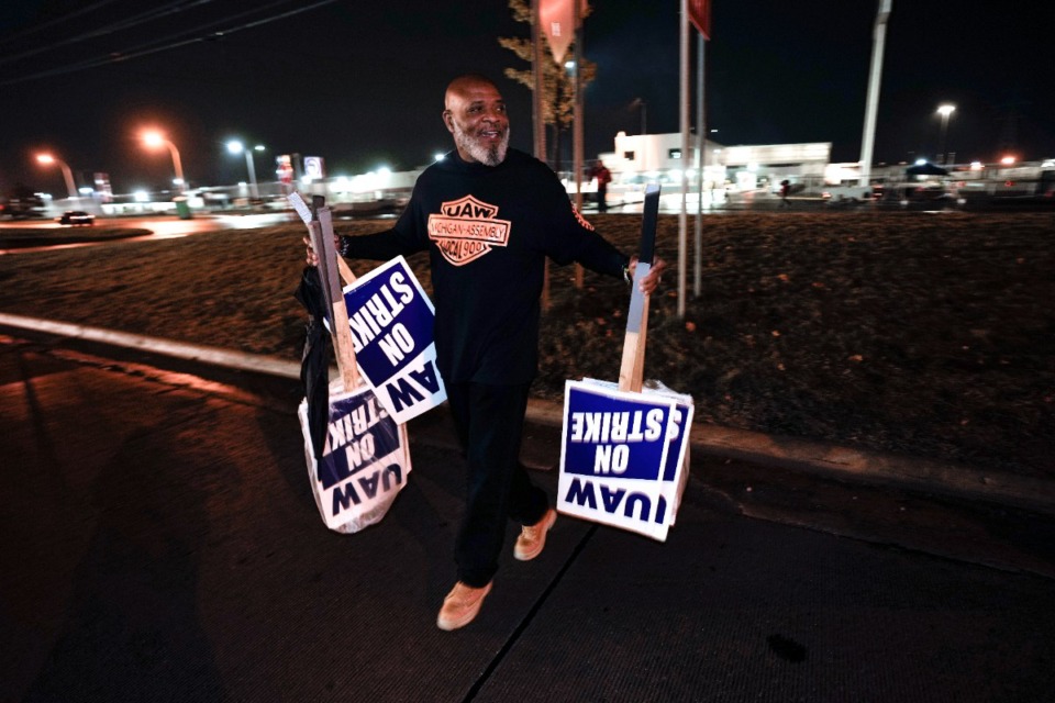 <strong>United Auto Workers member Marcel Edwards carries signs from the picket line to Local 900 headquarters at the Ford Michigan Assembly Plant in Wayne, Mich., Oct. 25. </strong>(Paul Sancya/AP file)