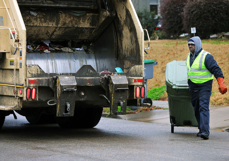 <strong>A sanitation worker hauls a garbage can to his truck in the Midtown neighborhood of Evergreen in January 2020.</strong> (Patrick Lantrip/The Daily Memphian file)