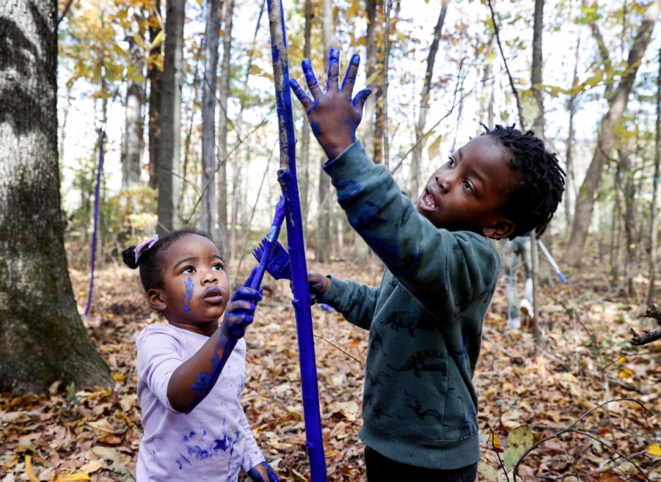 <strong>Volunteers Jamesia Newsome, 2, and brother James Newsome, 3, help apply pigement to trees, which are a part of Public Art Commission&rsquo;s project along the Wolf River Greenway on Nov. 13.</strong> (Mark Weber/The Daily Memphian)