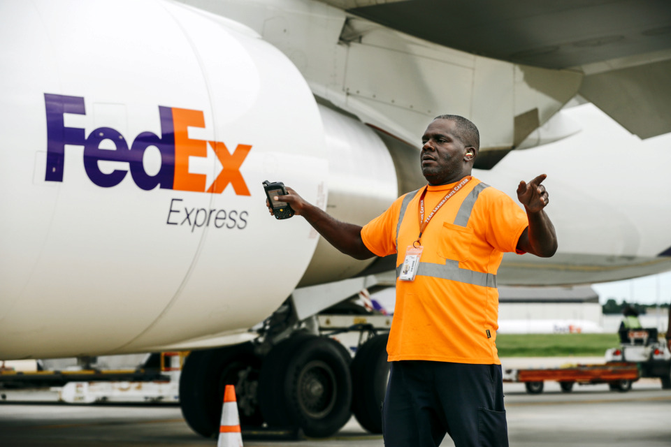 <strong>Anthony Givance, a team leader and gate captain at FedEx, directs a tug loaded with cargo to be shipped out on a FedEx Express jet. Company executives said weakness in global trade and industrial production contributed to FedEx Express&rsquo; poor showing in the fourth quarter.</strong>&nbsp;(Houston Cofield/Daily Memphian file)