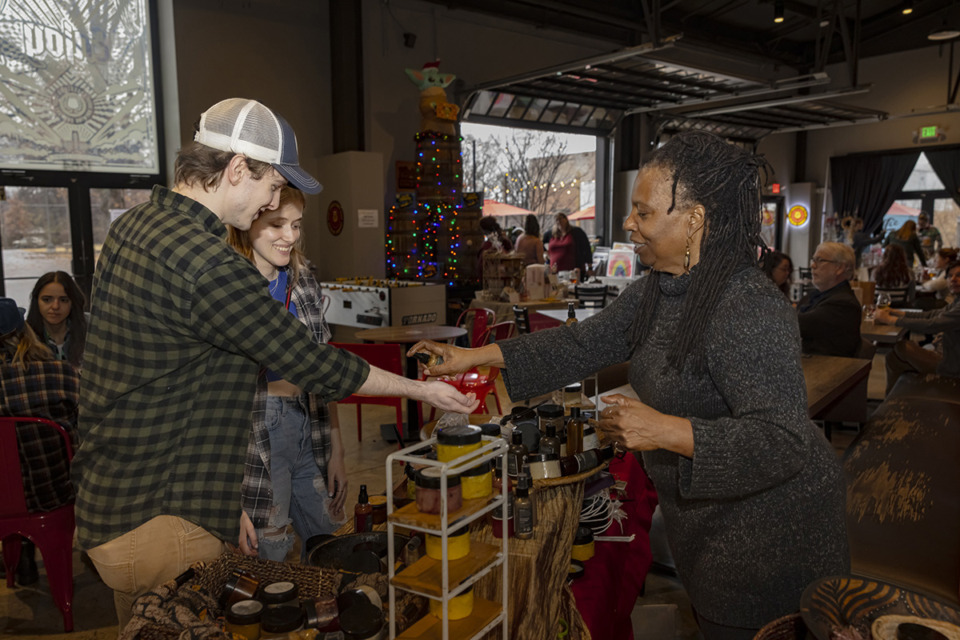<strong>Left to right: Levi Smith and Sarah Provence buy wares from Cynthia Johnson of Cynthia&rsquo;s Super Garden at the Last Minute Artist Market in Crosstown Brewing Co. on Dec. 23.</strong> (Ziggy Mack/Special to The Daily Memphian)