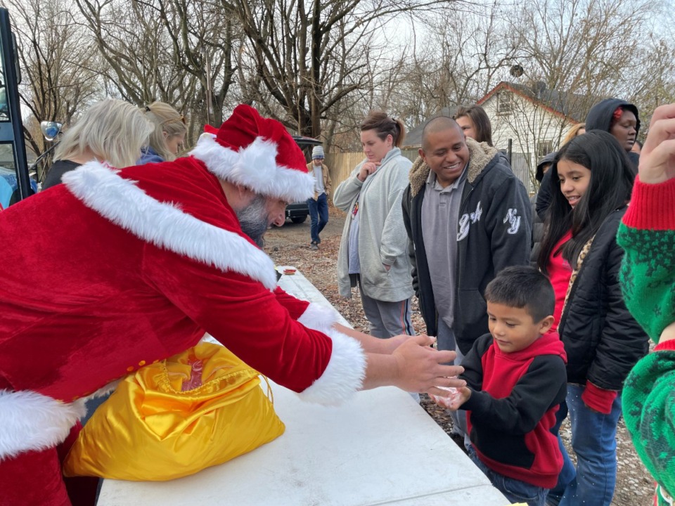 <strong>Santa Diego Ramirez passes out candy canes to children at the Sunshine &amp; Daisy gift distribution Sunday on Mamie Road in the Nutbush neighborhood.</strong> (Jane Roberts/The Daily Memphian)