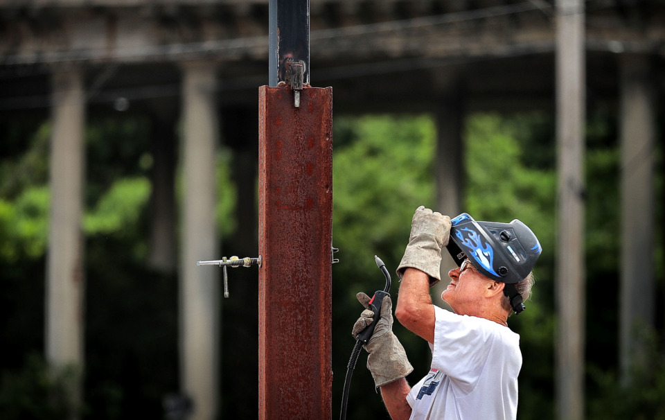 <strong>Tom Braswell, who owns several properties under the Poplar Avenue viaduct, installs a flag pole on July 3, 2019, near the aging bridge which will eventually be knocked down as TDOT moves forward on plans to replace the viaduct.</strong> (Jim Weber/Daily Memphian)