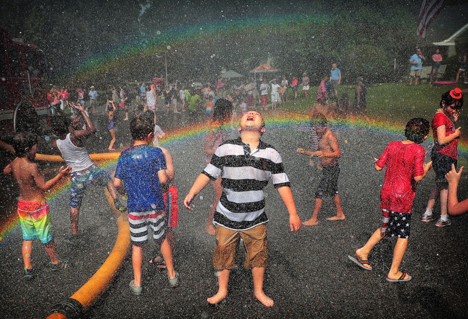 <strong>A rainbow illuminates a crowd of kids as they dance in the spray of the fire hose after the 70th annual Independence Day Parade in the High Point Terrace neighborhood on July 4, 2019. The patriotic gathering was one of several Fourth of July parades throughout Memphis Thursday.</strong> (Jim Weber/Daily Memphian)