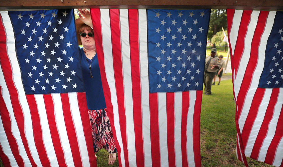 <strong>Lisa St. Gelais (left) hangs flags as a backdrop during the 70th annual Independence Day Parade in the High Point Terrace neighborhood on July 4, 2019.</strong> (Jim Weber/Daily Memphian)