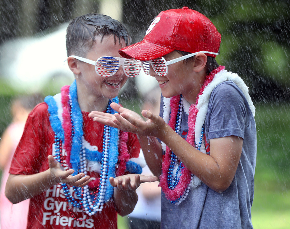 <strong>Cullen Weeden (left) and Ronan Keough (right) enjoy the impromptu splash pad provided by the Memphis Fire Department after the conclusion of the Central Gardens Fourth of July parade.</strong> (Patrick Lantrip/Daily Memphian)