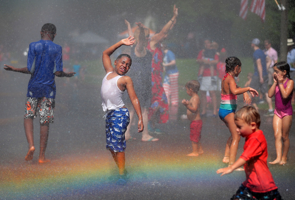 <strong>A rainbow illuminates Jacai Foster (center) and a crowd of kids as they dance in the spray of the fire hose after the 70th annual Independence Day Parade in the High Point Terrace neighborhood on July 4, 2019. Once again East Memphis residents gathered for a patriotic morning of star-spangled bikes, waving neighbors and a dousing by the Memphis Fire Department.</strong> (Jim Weber/Daily Memphian)