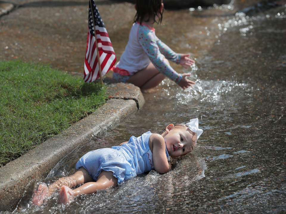 <strong>Two-year-old Anne Tipton Rogers relaxes in the cool runoff from the fire hose as kids play in the spray after the 70th annual Independence Day Parade in the High Point Terrace neighborhood on July 4, 2019. Once again East Memphis residents gathered for a patriotic morning of star-spangled bikes, waving neighbors and a dousing by the Memphis Fire Department.</strong> (Jim Weber/Daily Memphian)