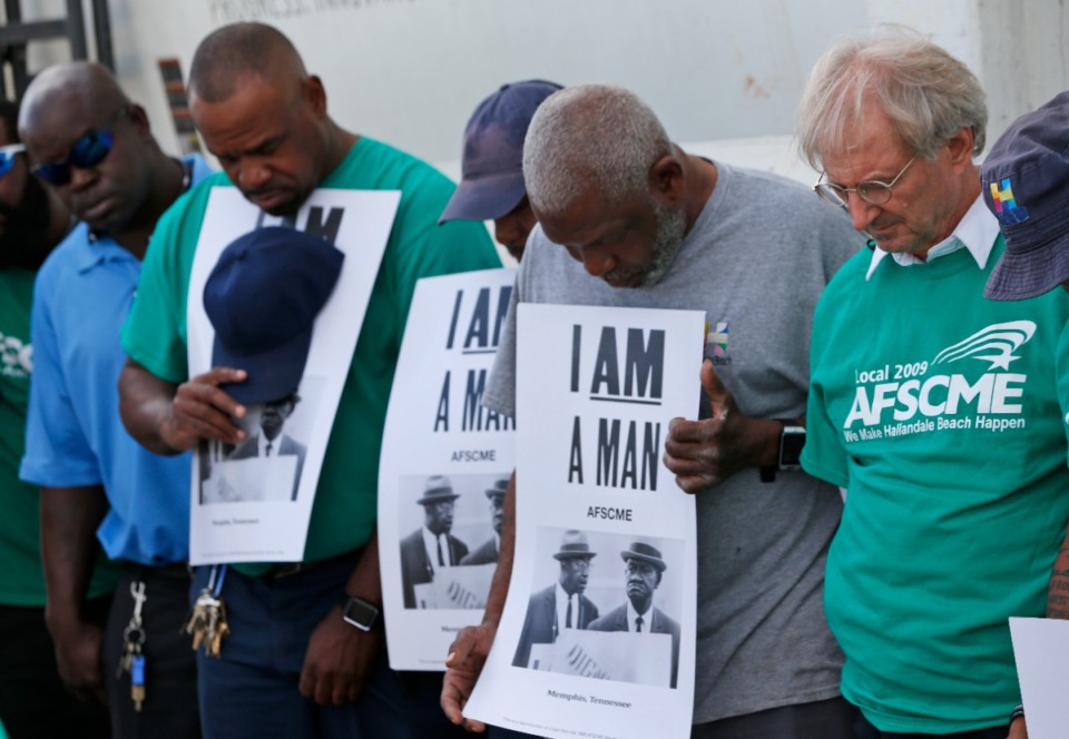 <strong>City officials and workers in Florida bow their heads Feb. 1, 2018, during a Moment of Silence to honor two Memphis sanitation workers, Echol Cole and Robert Walker, killed by a malfunctioning garbage truck on Feb. 1, 1968.</strong> (AP Photo/Wilfredo Lee)