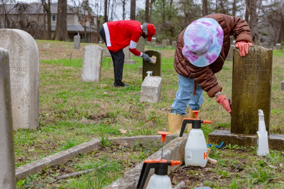<strong>Volunteers Sydni Williams (right) and Ethel Morris scrub tombstones at Zion Christian Cemetery on Saturday, March 9, 2024. The cemetery is in the Curve neighborhood in South Memphis.</strong> (Ziggy Mack/Special to The Daily Memphian)