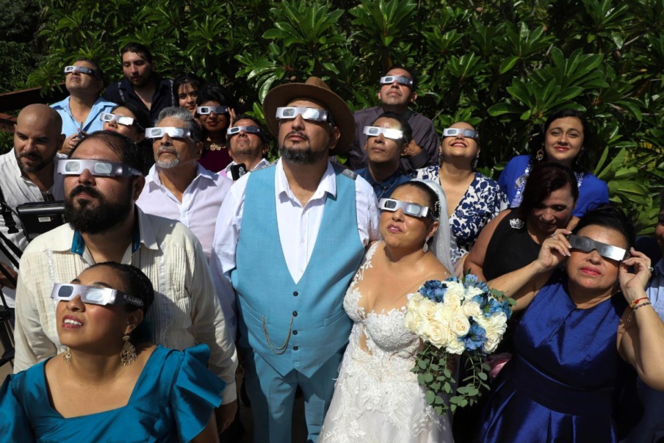 <strong>Groom Isaac Medina, center, and bride Jazmin Gonzalez, watch an annular solar eclipse before the start of their wedding ceremony, in Merida, Mexico, Oct. 14, 2023. A total solar eclipse will occur in many U.S. states on April 8, 2024.</strong> (Martin Zetina/AP File)