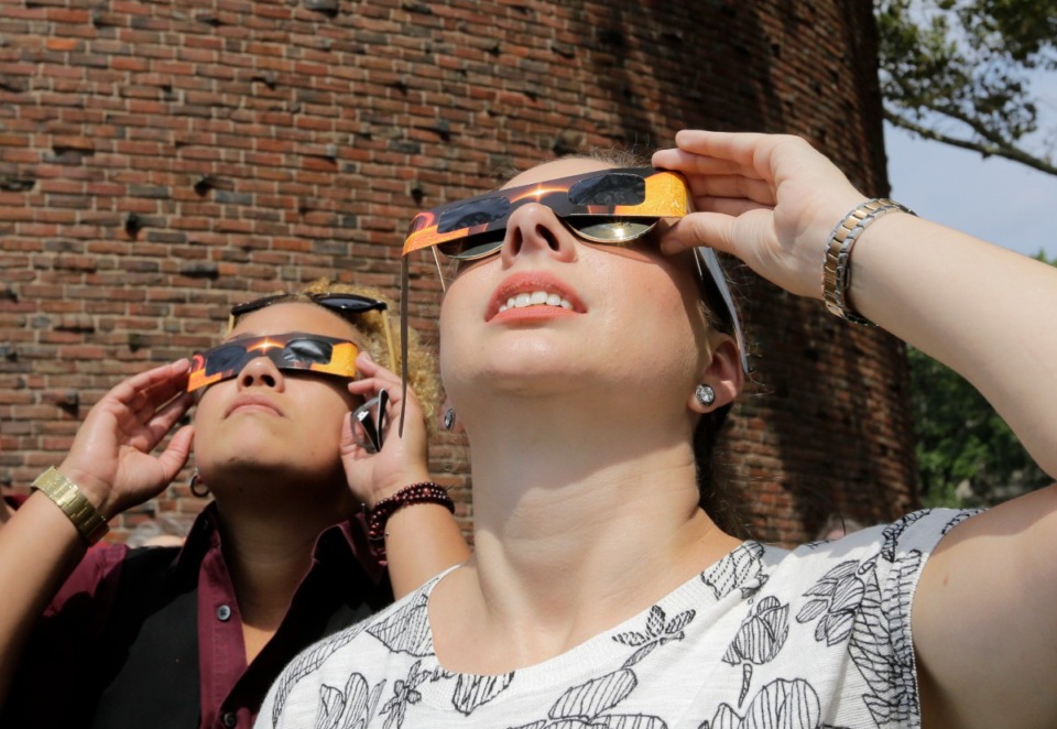<strong>Liz Jason, of Boston, right, uses protective eclipse glasses to view a partial solar eclipse, Monday, Aug. 21, 2017, on the campus of Massachusetts Institute of Technology, in Cambridge, Mass.</strong> (AP Photo/Steven Senne)