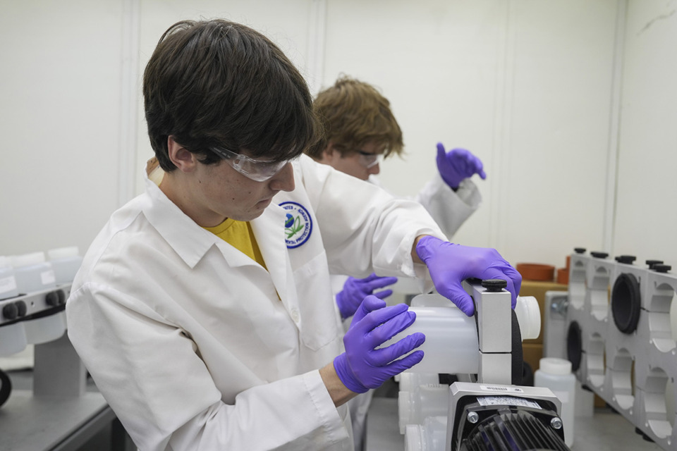 <strong>Jackson Quinn, foreground, places a bottle contains a PFAS water sample into a rotator April 10 at a U.S. Environmental Protection Agency lab in Cincinnati. The Environmental Protection Agency Wednesday announced its first-ever limits for several common types of PFAS, the so-called "forever chemicals," in drinking water.</strong> (Joshua A. Bickel/AP file)