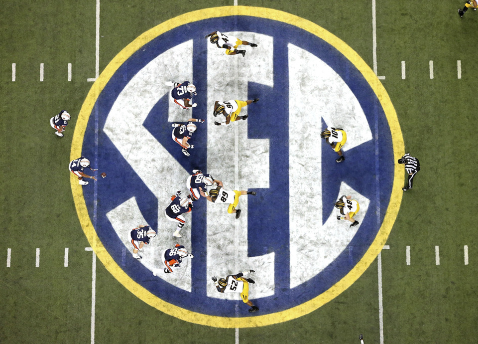 <strong>Auburn quarterback Nick Marshall (14), left, takes the snap from Auburn center Reese Dismukes (50) as the Auburn offense operates against Missouri on the SEC logo during the first half of Auburn's 59-42 win over Missouri in the SEC Championship at the Georgia Dome, Saturday, Dec. 7, 2013, in Atlanta, Ga. Southeastern Conference and Pac-12 officials are expected to provide the final approval of a $2.8 billion plan that will settle antitrust claims and set the stage for college athletes to start sharing the billions of dollars flowing to their schools.</strong> (Jason Getz/AP Photo via Atlanta Journal-Constitution file)