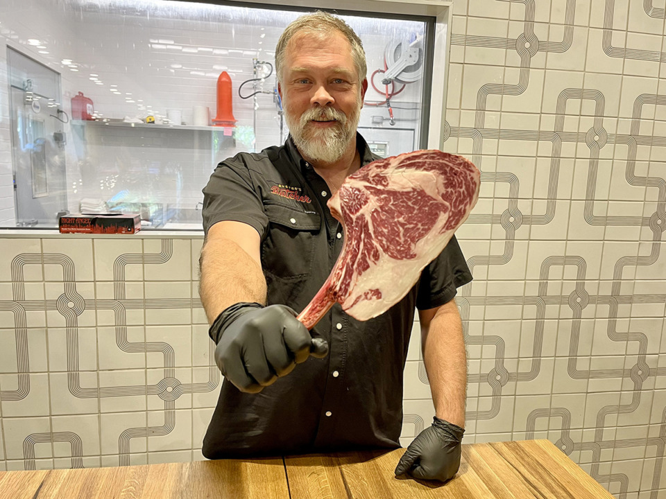 <strong>Buster's Butcher head butcher Brad McCarley holds a cut-to-order tomahawk steak. The East Memphis butcher shop opened in 2023.</strong> (Jennifer Chandler/The Daily Memphian)