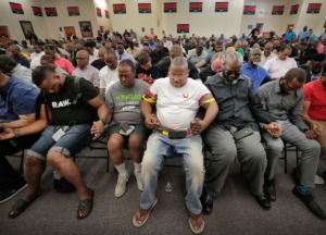 <strong>Willie Herenton supporters clasp hands for prayer during a Donuts With Doc rally at the mayoral candidate's campaign headquarters in South Memphis on Aug. 3, 2019.</strong> (Jim Weber/Daily Memphian)