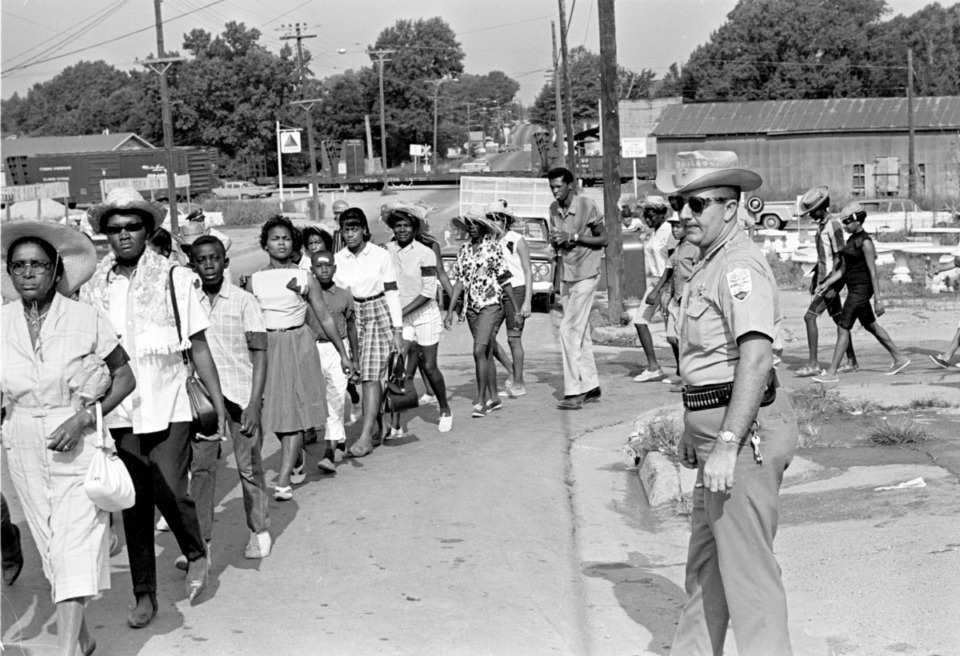 <strong>Neshoba County Deputy Sheriff Cecil Price watches marchers as they pass through Philadelphia, Miss., during a memorial for three slain Civil Rights workers, June 21, 1965. Price is charged with conspiracy to violate the civil rights of the three Freedom Summer activists slain by Klansmen in 1964. Seven Ku Klux Klansmen were convicted of federal civil rights violations in the deaths and sentenced to prison terms ranging from three to ten years; none served more than six years.</strong> (Jack Thornell/AP file)