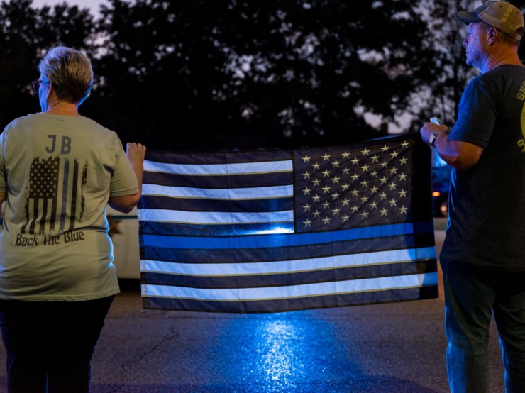 <strong>Melanie and Jimmy Busch hold up a flag in respect while watching Wednesday&rsquo;s Sea of Blue event.&nbsp;</strong>(Brad Vest/Special to The Daily Memphian)