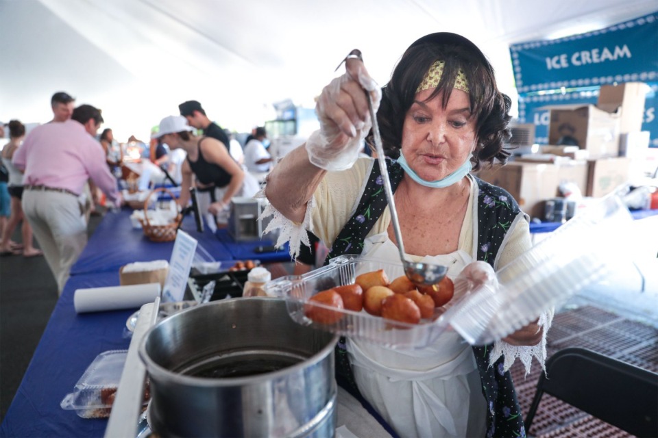 <strong>Yolanta Matika drizzles warm honey on an order of loukoumades at the Memphis Greek Festival May 20, 2022.</strong> (Patrick Lantrip/The Daily Memphian file)