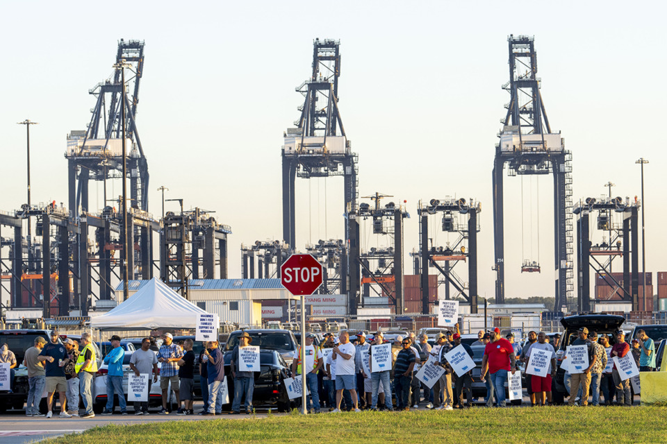 <strong>Shipping container cranes are visible in the background as longshoremen carry signs and chant Oct. 1 outside the Bayport Container Terminal in Seabrook, Texas, as members of the International Longshoreman's Association have decided to strike after their contract expired at midnight.</strong> (Kirk Sides/Houston Chronicle via AP file)