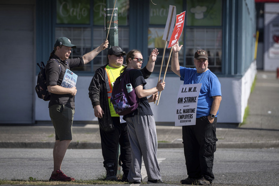 <strong>International Longshore and Warehouse Union workers wave at cars driving past while picketing outside of the BC Maritime Employers Association Dispatch Center after a 72 hour strike notice and no agreement made on the bargaining table in Vancouver, on Saturday, July 1, 2023.</strong> (Ethan Cairns/The Canadian Press via AP file)