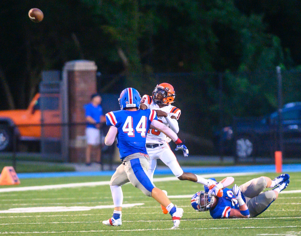 <strong>Ridgeway quarterback Anterrion Martin (in orange) releases the ball as MUS's Elliot Allen hangs on to his foot and Robert Dickinson (44) pursues him Friday night at MUS.</strong> (Greg Campbell/Special to the Daily Memphian)