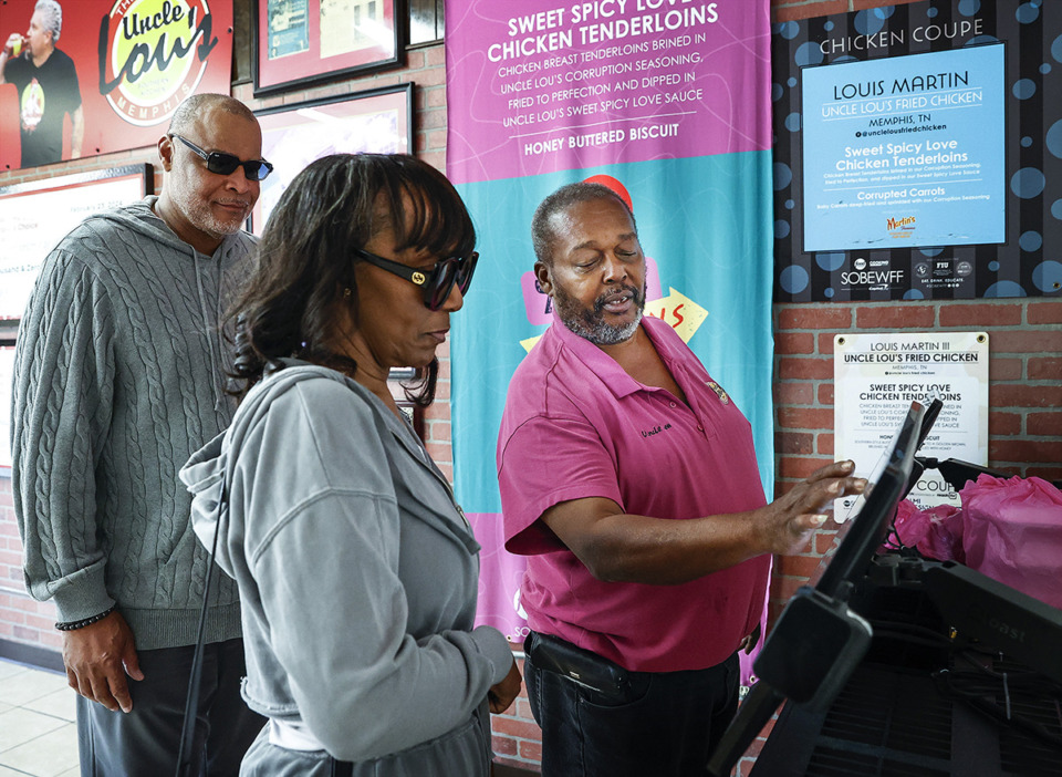 <strong>Uncle Lou's Fried Chicken owner Lou Martin (right) helps customers use the new ordering kiosk.</strong> (Mark Weber/The Daily Memphian)