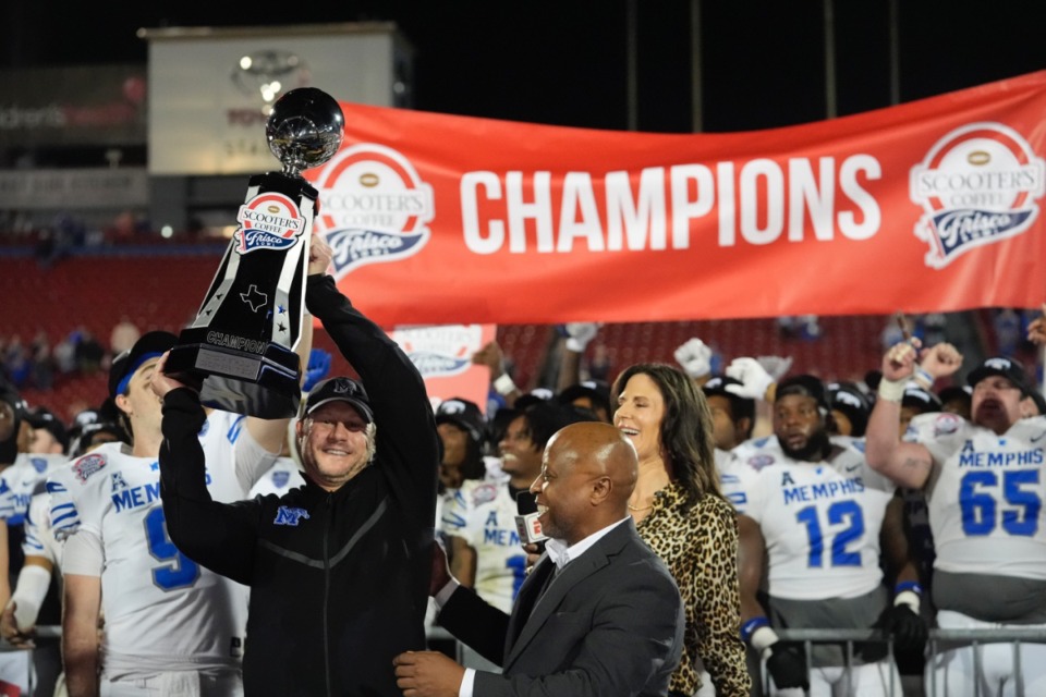 <strong>Memphis coach Ryan Silverfield, left, lifts the Frisco Bowl trophy after beating West Virginia on Tuesday night in Frisco, Texas.</strong> (AP Photo/LM Otero)