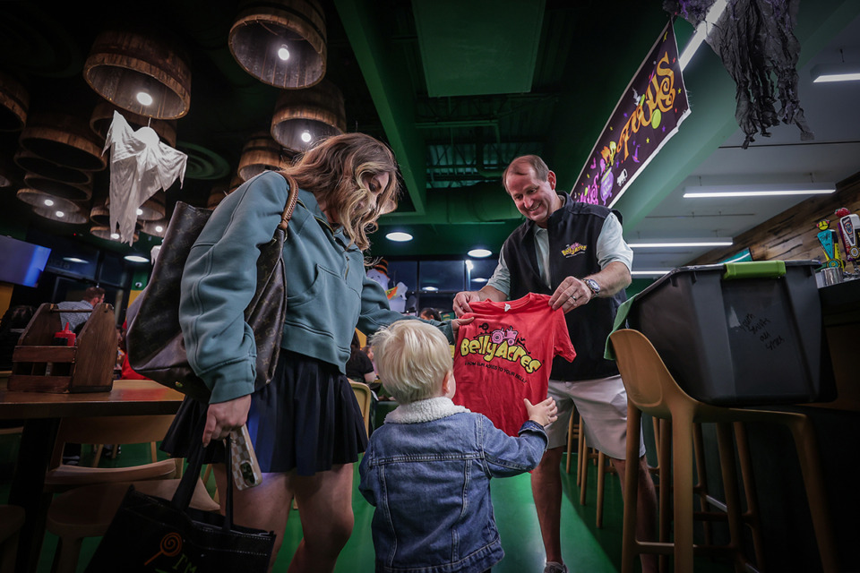 <strong>Owner Lee Scifres hands a free Belly Acres T-shirt to Grayson Rieckhoff and his mother Laura on Oct. 17, 2023.</strong> (Patrick Lantrip/The Daily Memphian file)