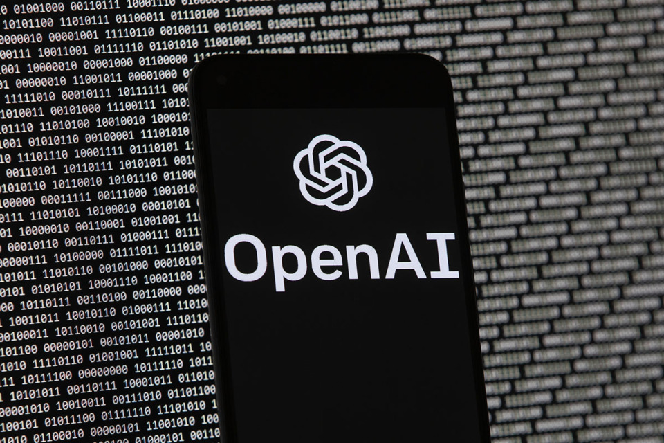 <strong>The OpenAI logo appears on a mobile phone in front of a computer screen with random binary data, March 9, 2023, in Boston.</strong> (Michael Dwyer/AP Photo file)