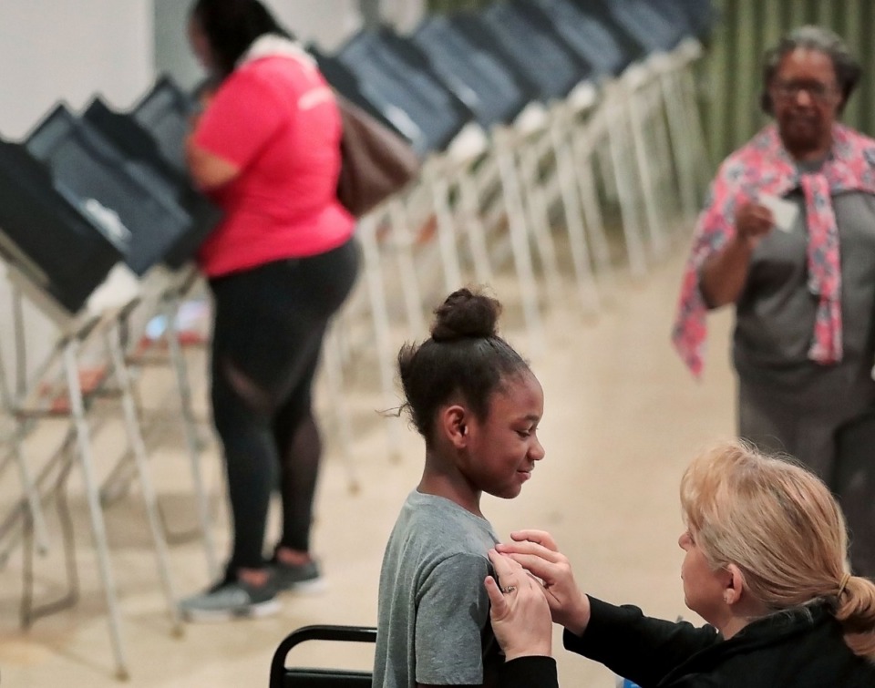 <strong>Imani Woods, 9, gets an "I voted today" sticker from poll worker Sara Ice as candidates and pollsters make a final effort to edge ahead during the last day of early voting at Abundant Grace Fellowship Church on Sept. 28.</strong> (Jim Weber/Daily Memphian)